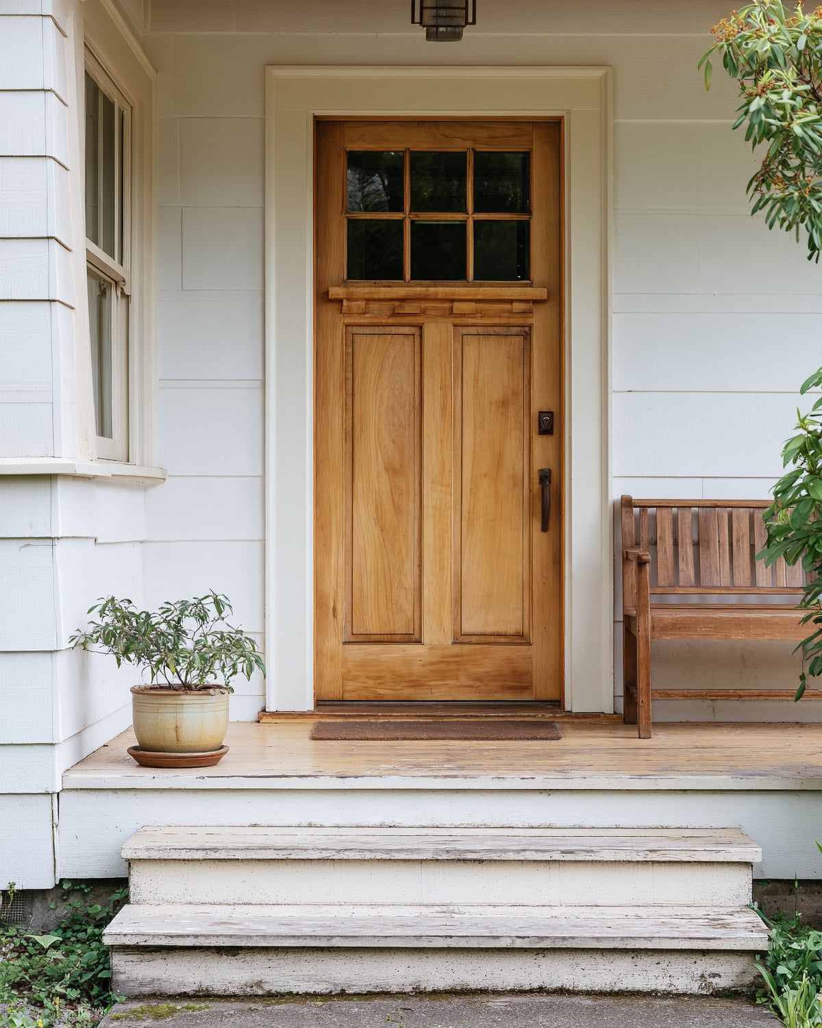 Illustrative wood front door opening onto a simple porch with a bench and planter.